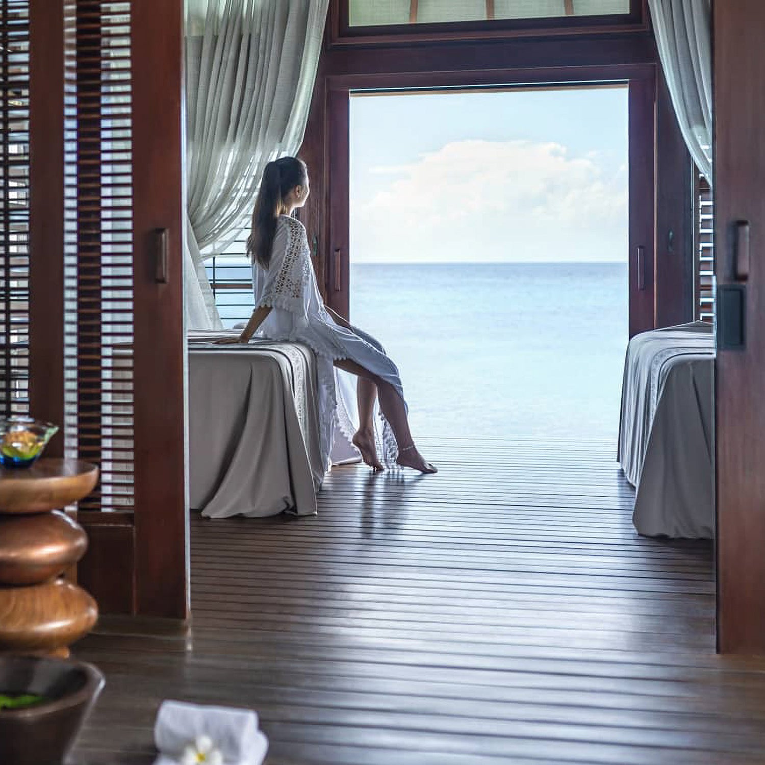 Four Seasons Resort Maldives at Landaa Giraavaru. A woman in villa looking out at the sea. Teresa Tarmey super facialist residency at Four Seasons Resort Maldives