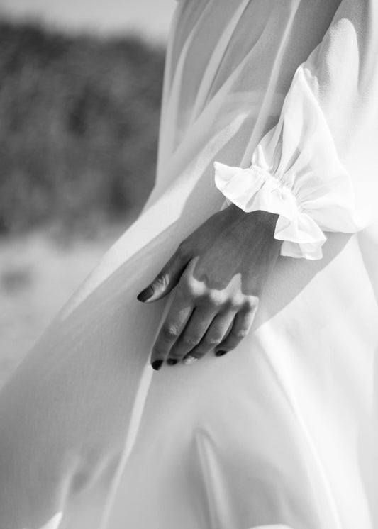 An arty image of white dress and short dark manicured nails. Signature TT Facial at Teresa Tarmey
